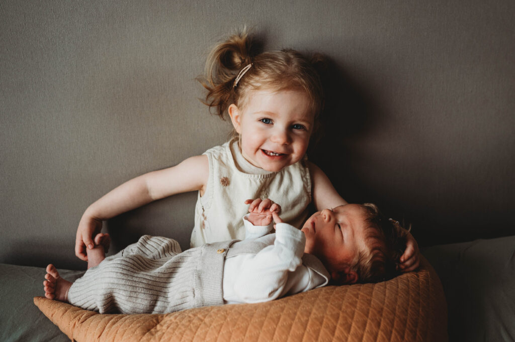 große Schwester hält den neugeborenen kleinen Baby Bruder im Arm